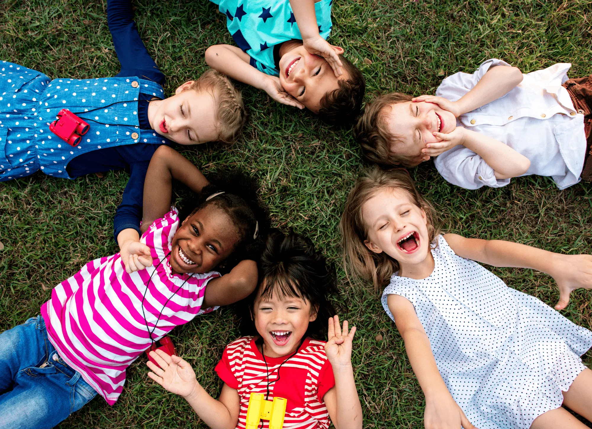 Children smiling while laying in the grass